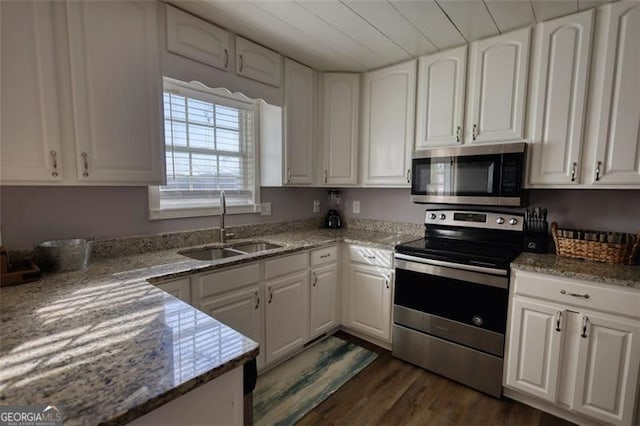 kitchen with appliances with stainless steel finishes, dark hardwood / wood-style floors, white cabinets, light stone counters, and sink