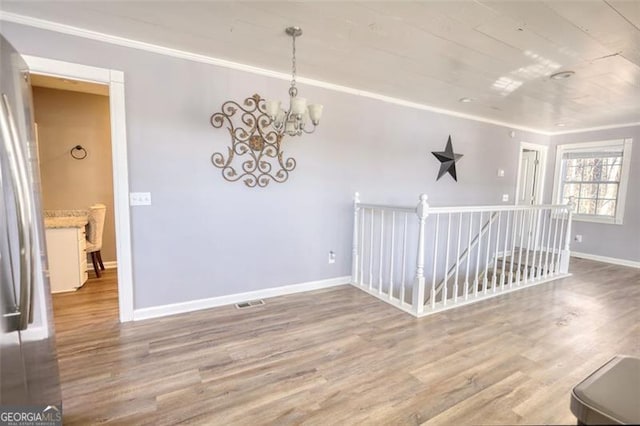 empty room featuring hardwood / wood-style flooring, crown molding, and a chandelier