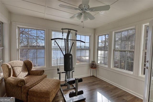 sunroom / solarium with ceiling fan and a water view