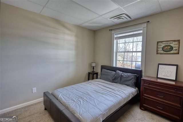 bedroom with light colored carpet and a drop ceiling