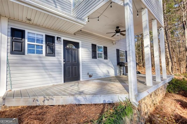 view of exterior entry with ceiling fan and a deck