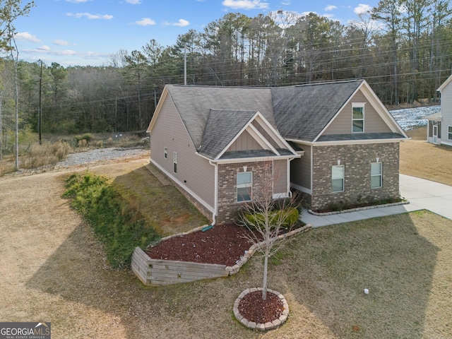 view of front of property featuring driveway, roof with shingles, board and batten siding, and brick siding