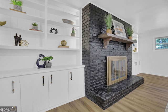 details featuring built in shelves, a brick fireplace, and hardwood / wood-style floors