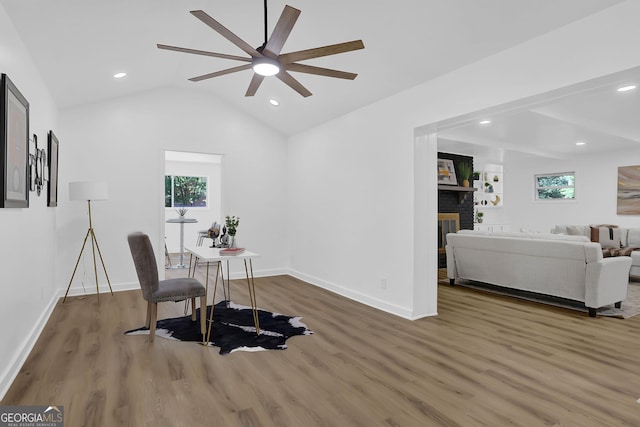 office space featuring ceiling fan, wood-type flooring, a fireplace, and lofted ceiling