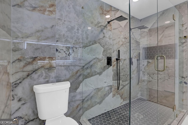 bathroom featuring a shower with shower door and toilet