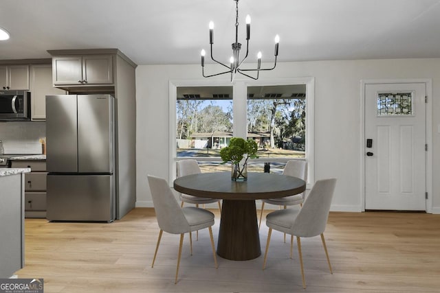 dining room with light wood finished floors, a chandelier, and baseboards