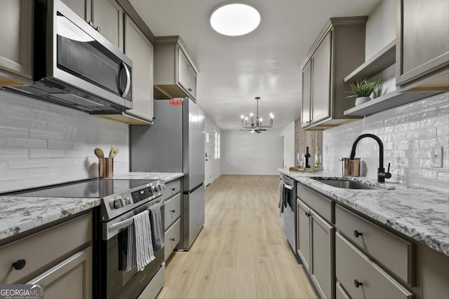 kitchen with pendant lighting, light hardwood / wood-style floors, sink, an inviting chandelier, and stainless steel appliances