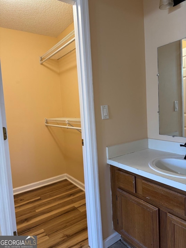 bathroom with hardwood / wood-style flooring, vanity, and a textured ceiling