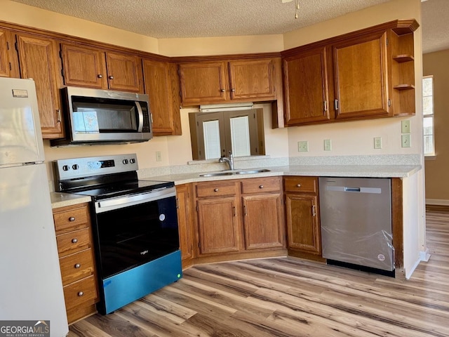 kitchen with appliances with stainless steel finishes, sink, light hardwood / wood-style floors, a textured ceiling, and french doors