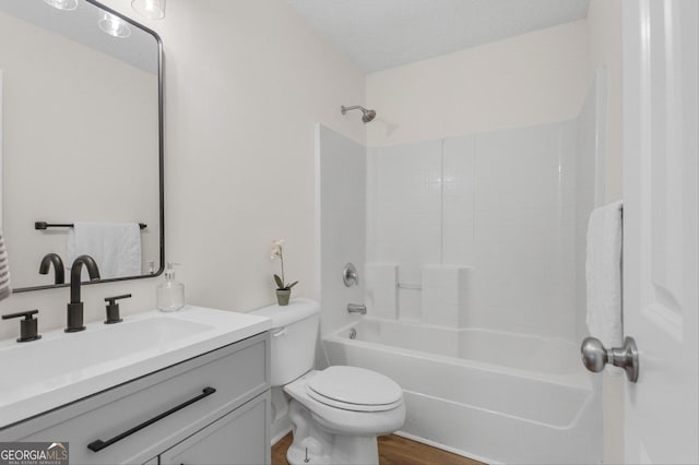 full bathroom featuring toilet, vanity, hardwood / wood-style floors,  shower combination, and a textured ceiling