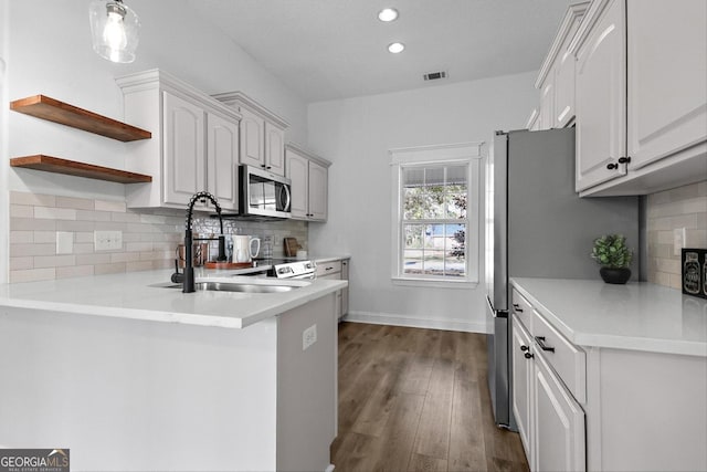 kitchen featuring kitchen peninsula, dark hardwood / wood-style floors, backsplash, white cabinets, and sink