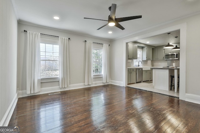 unfurnished living room featuring ceiling fan, dark wood-type flooring, sink, and crown molding