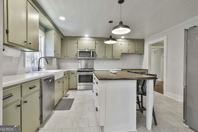 kitchen with stainless steel appliances, green cabinetry, a kitchen island, a breakfast bar, and sink