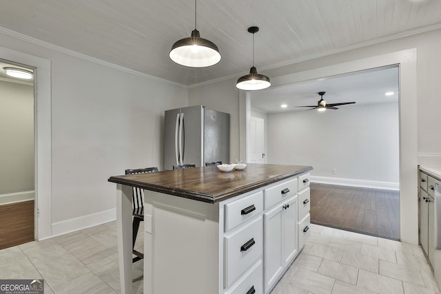 kitchen featuring pendant lighting, a kitchen island, white cabinets, stainless steel fridge, and wood counters