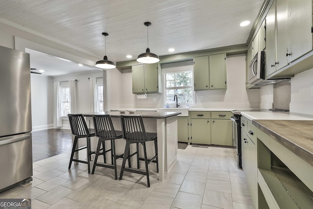 kitchen with a kitchen bar, green cabinets, crown molding, appliances with stainless steel finishes, and light tile patterned floors