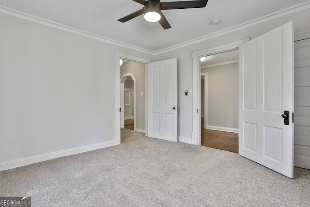 unfurnished bedroom featuring ceiling fan, light carpet, and crown molding