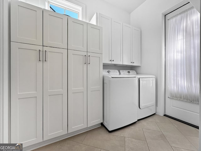 washroom with light tile patterned floors, washing machine and dryer, and cabinets