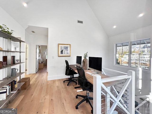 home office featuring high vaulted ceiling and light hardwood / wood-style floors