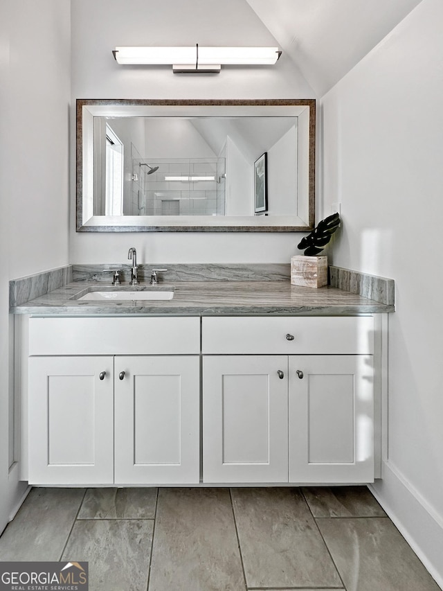 bathroom featuring a shower, vanity, and vaulted ceiling