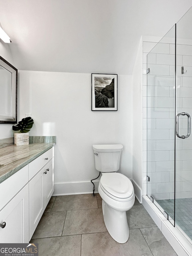 bathroom featuring toilet, vanity, tile patterned flooring, and a shower with door