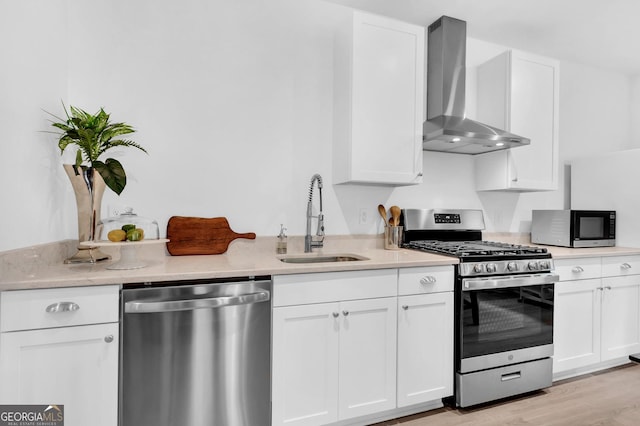 kitchen with sink, white cabinetry, appliances with stainless steel finishes, and wall chimney exhaust hood