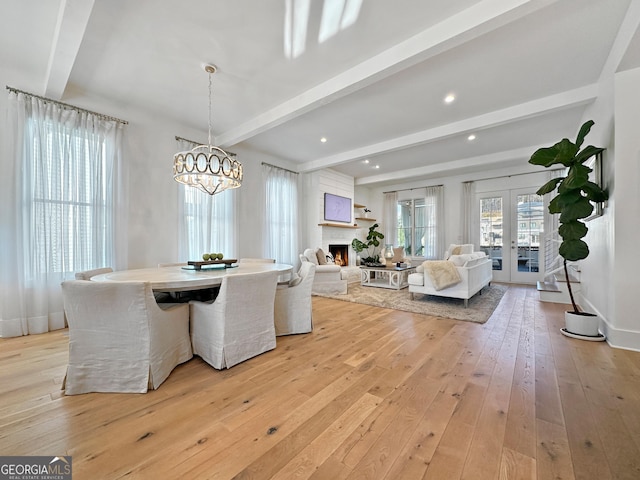 dining space featuring french doors, a fireplace, beamed ceiling, an inviting chandelier, and light hardwood / wood-style flooring