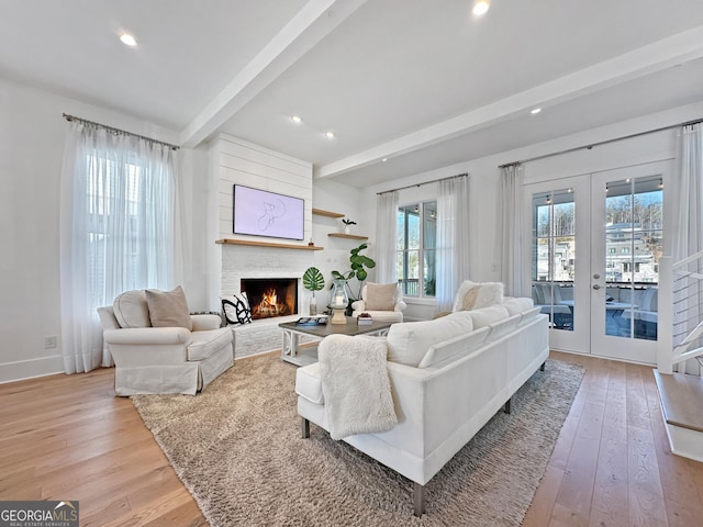 living room featuring light hardwood / wood-style floors, beam ceiling, french doors, and a fireplace