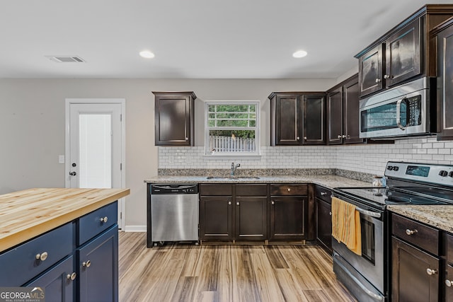 kitchen with sink, dark brown cabinetry, stainless steel appliances, and wood counters