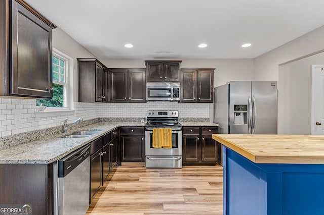 kitchen with light hardwood / wood-style floors, sink, stainless steel appliances, dark brown cabinets, and light stone counters