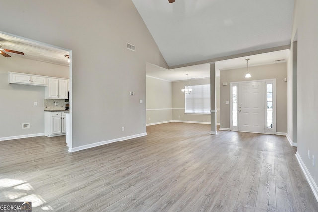 entrance foyer featuring light wood-type flooring, ceiling fan with notable chandelier, and high vaulted ceiling