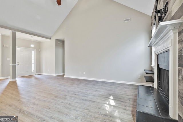 unfurnished living room with a wealth of natural light, ceiling fan, hardwood / wood-style flooring, high vaulted ceiling, and a tiled fireplace