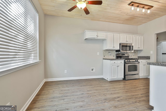 kitchen with wooden ceiling, appliances with stainless steel finishes, white cabinetry, and tasteful backsplash