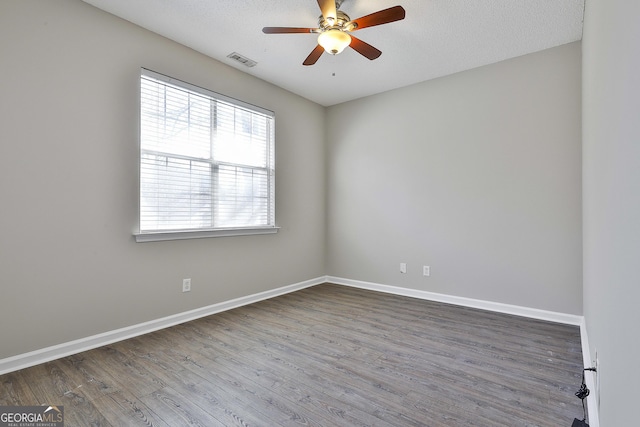 empty room featuring ceiling fan, wood-type flooring, and a textured ceiling