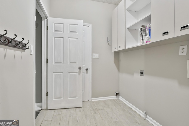 laundry room featuring cabinets, light hardwood / wood-style floors, and electric dryer hookup