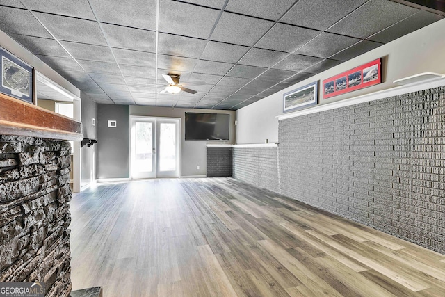 unfurnished living room featuring ceiling fan, wood-type flooring, a paneled ceiling, and french doors