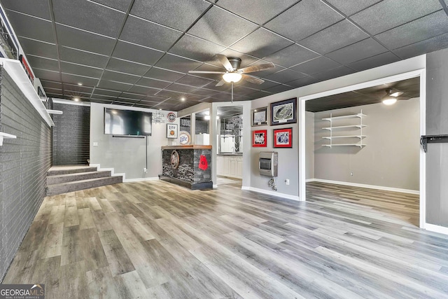 basement with a paneled ceiling, heating unit, hardwood / wood-style flooring, and a multi sided fireplace