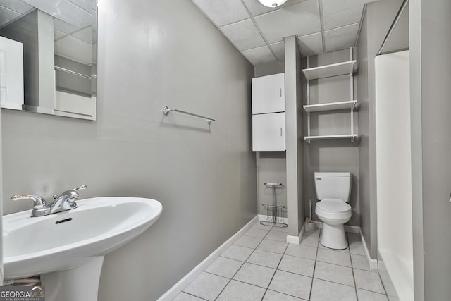 bathroom featuring toilet, tile patterned floors, a drop ceiling, and sink