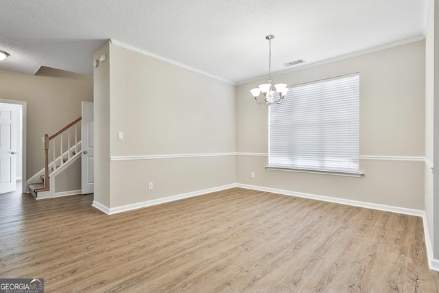 spare room featuring light hardwood / wood-style flooring, ornamental molding, a notable chandelier, and a healthy amount of sunlight