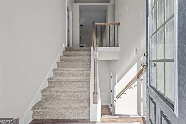 staircase with visible vents, baseboards, and wood finished floors