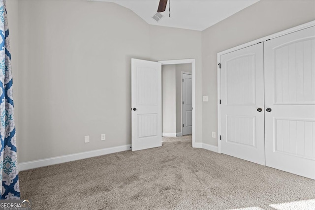 unfurnished bedroom with baseboards, vaulted ceiling, a closet, and light colored carpet