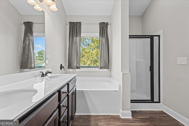 full bath featuring a garden tub, a sink, a shower stall, wood finished floors, and baseboards