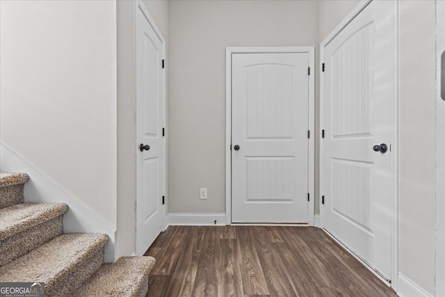 foyer with dark wood-style floors, baseboards, and stairway