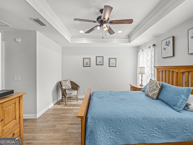 bedroom featuring a raised ceiling, ceiling fan, crown molding, and light hardwood / wood-style floors