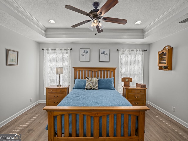 bedroom with ceiling fan, a raised ceiling, and multiple windows