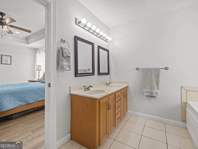 bathroom with ceiling fan, vanity, tile patterned floors, a raised ceiling, and a textured ceiling