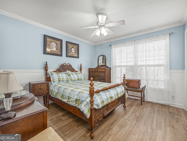 bedroom with ceiling fan, light wood-type flooring, crown molding, and a textured ceiling