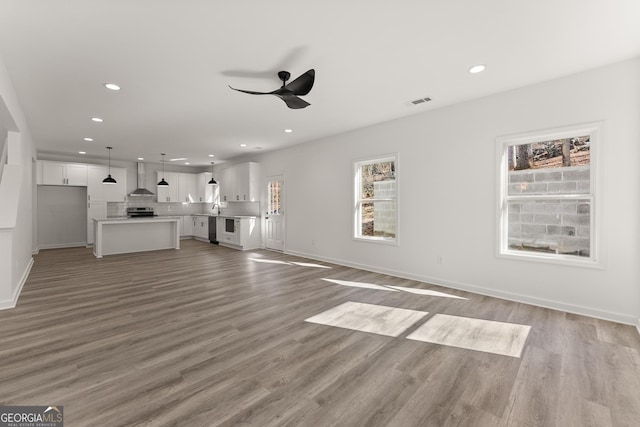 unfurnished living room with visible vents, baseboards, ceiling fan, light wood-type flooring, and recessed lighting