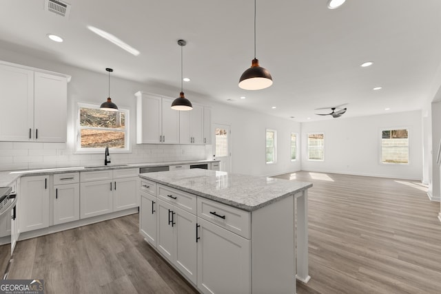 kitchen featuring visible vents, light wood-style floors, decorative backsplash, and a sink
