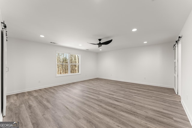 unfurnished room featuring visible vents, a barn door, recessed lighting, wood finished floors, and a ceiling fan
