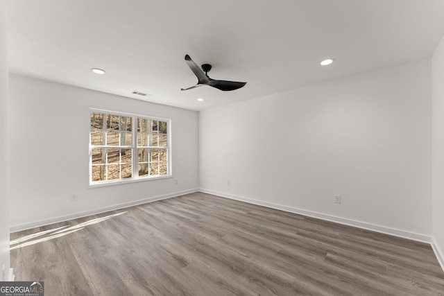 spare room featuring recessed lighting, baseboards, and dark wood-style flooring